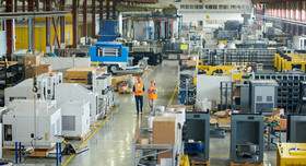 Zwei Industrie-Beschäftigte laufen durch den Flur einer Fabrikhalle. 