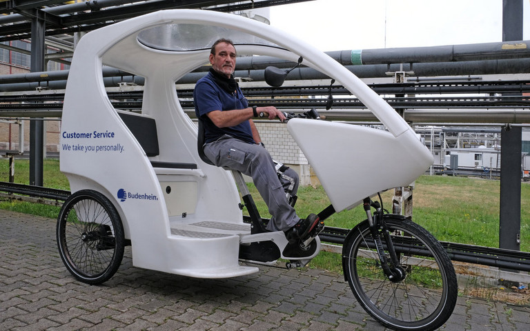 Haustechniker Wolfgang Wilke ist mit einer der drei Rikschas mit Elektroantrieb unterwegs, die die Chemische Fabrik Budenheim ihren Mitarbeitern zur Verfügung stellt. Foto: Wir.Hier. / Florian Lang