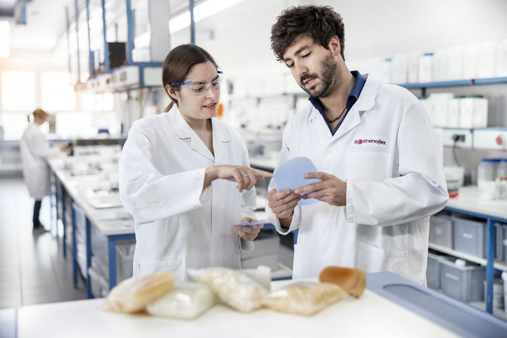 Zwei Menschen mit Laborkitteln halten Rohstoffe für die Kunststoffherstellung in der Hand.
