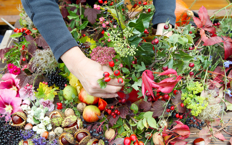 Floristin erstellt aus Weinlaub, Kastanien und Hagebutten ein farbenfrohes Gesteck.