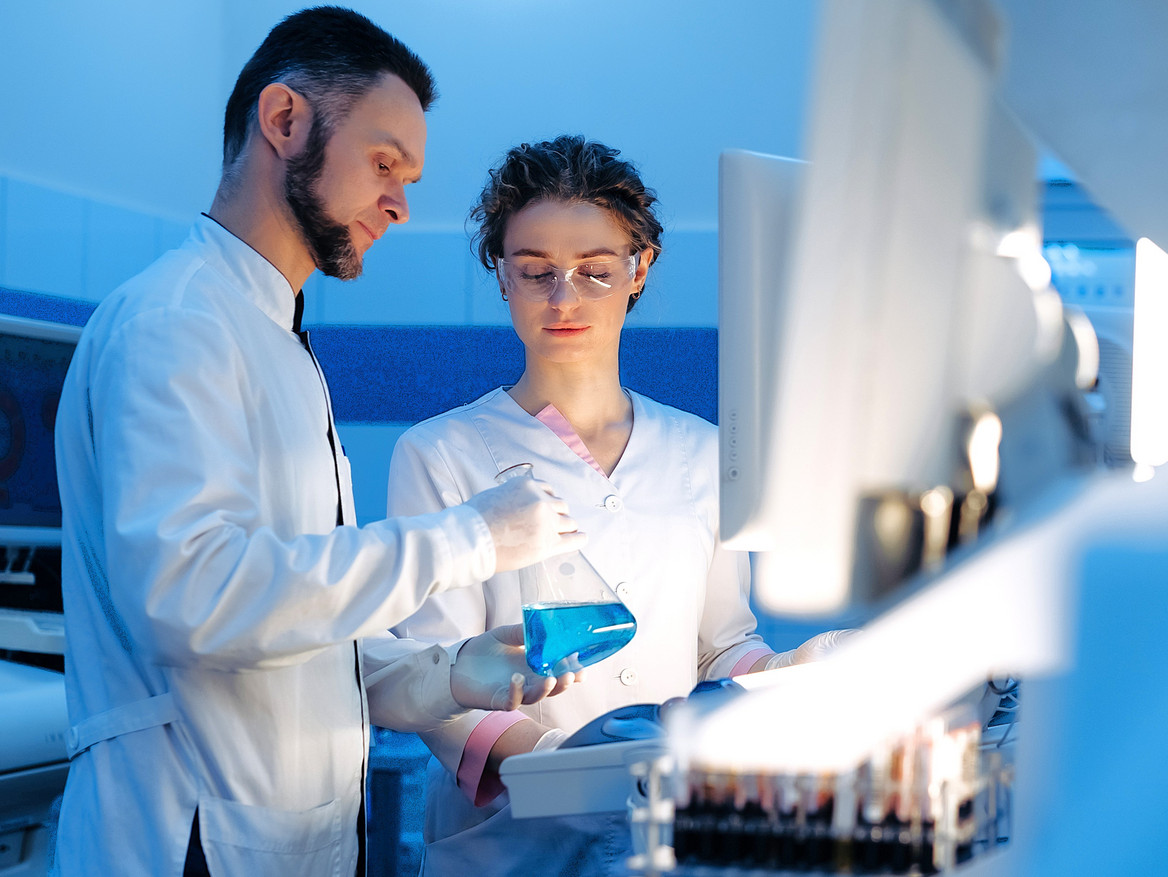 Eine männliche und eine weibliche Pharma-Fachkraft arbeiten zusammen in einem Laobor. 