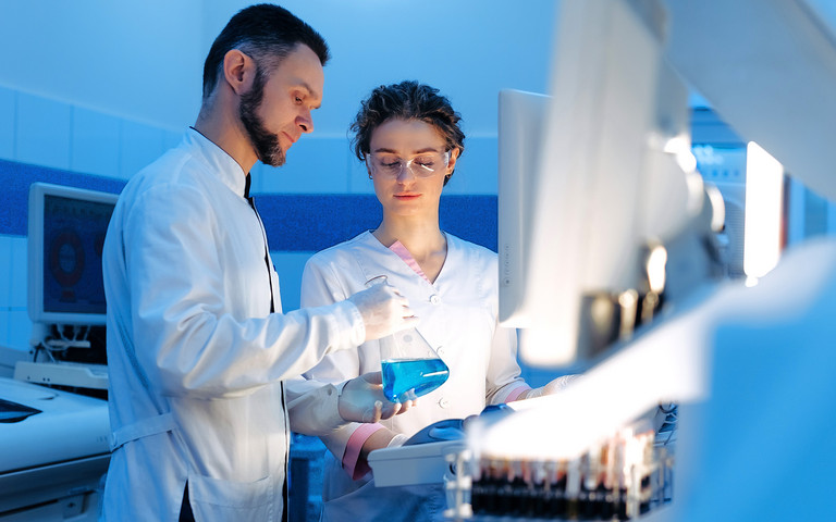 Eine männliche und eine weibliche Pharma-Fachkraft arbeiten zusammen in einem Laobor. 