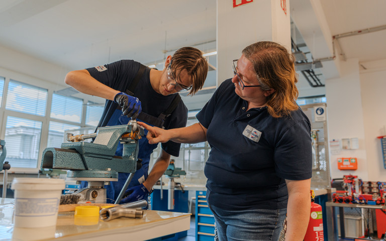 Kristina Eckert,trainer at FUCHS LUBRICANTS GERMANY, guides an apprentice working on a component in the company’s training workshop.