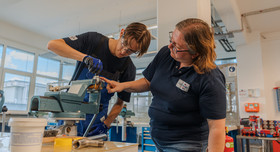 Kristina Eckert,trainer at FUCHS LUBRICANTS GERMANY, guides an apprentice working on a component in the company’s training workshop.