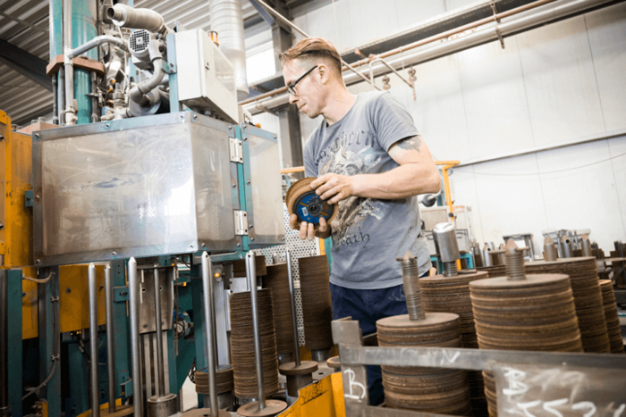 Produktionsmitarbeiter Christoph Müller entnimmt Scheiben aus einem Fertigungsautomaten.