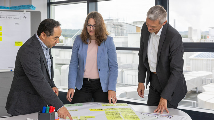  Drei Personen stehen an einem Tisch und unterhalten sich. Foto: Frank Eppler / IW Medien