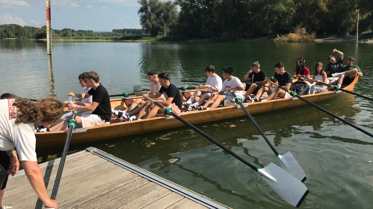 Die neuen Auszubildenden des Unternehmens Thor rudern gemeinsam in einem Holzboot auf einem Fluss.