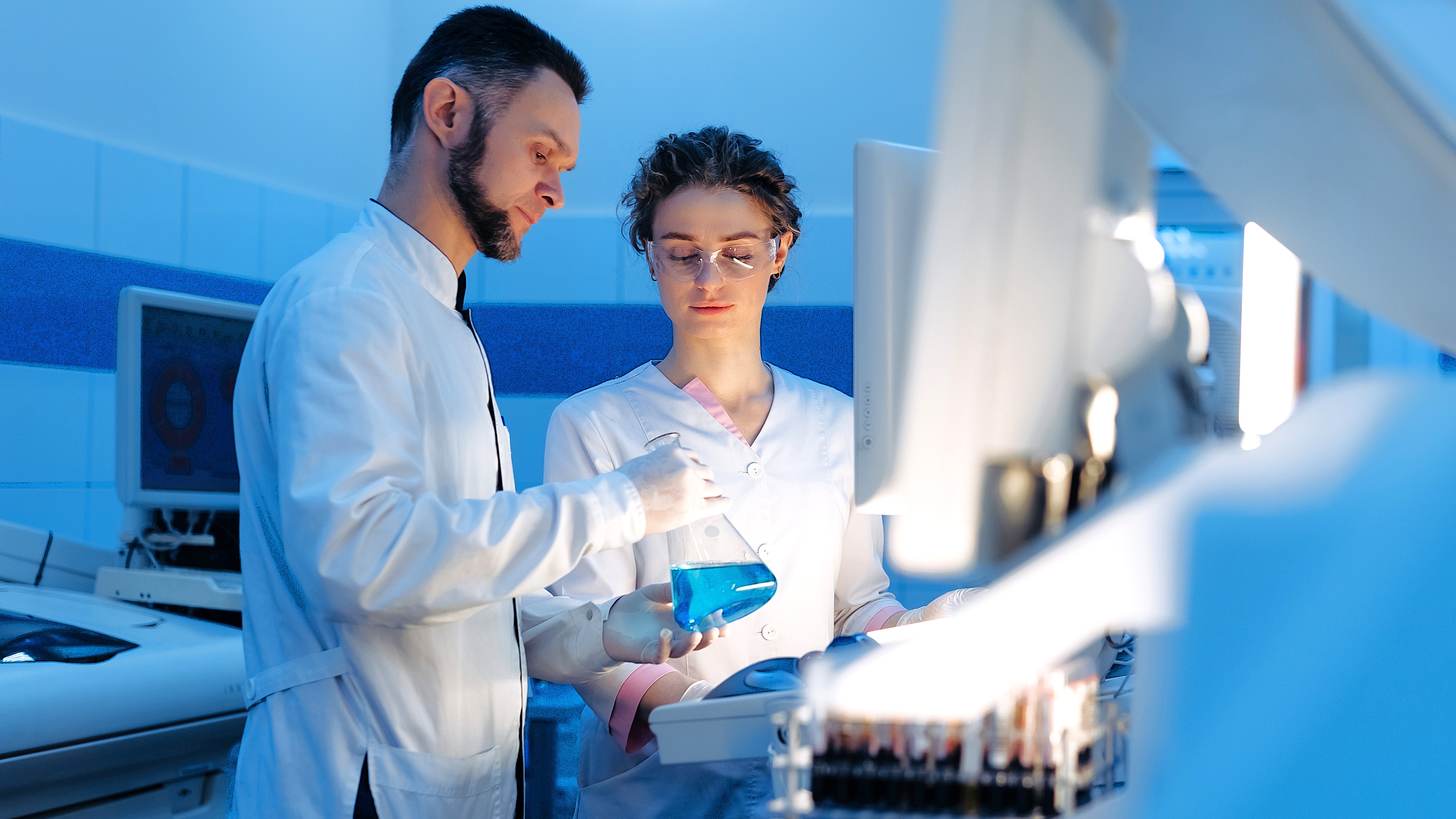 Eine männliche und eine weibliche Pharma-Fachkraft arbeiten zusammen in einem Laobor. 