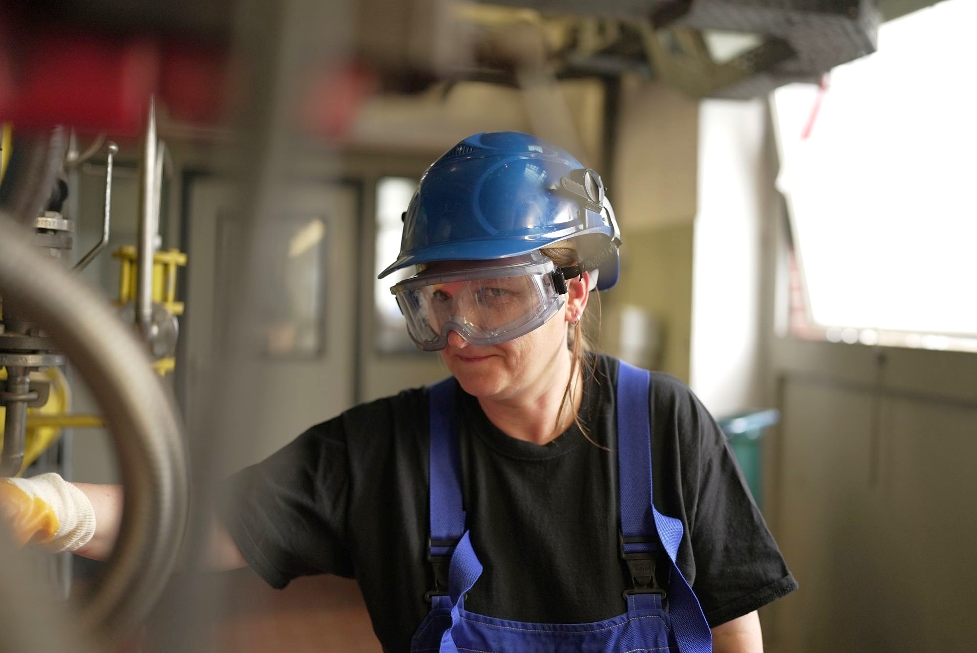 Chemikantin und Kesselwärterin prüft während eines chemischen Prozesses die Steuerungen der Anlage. 