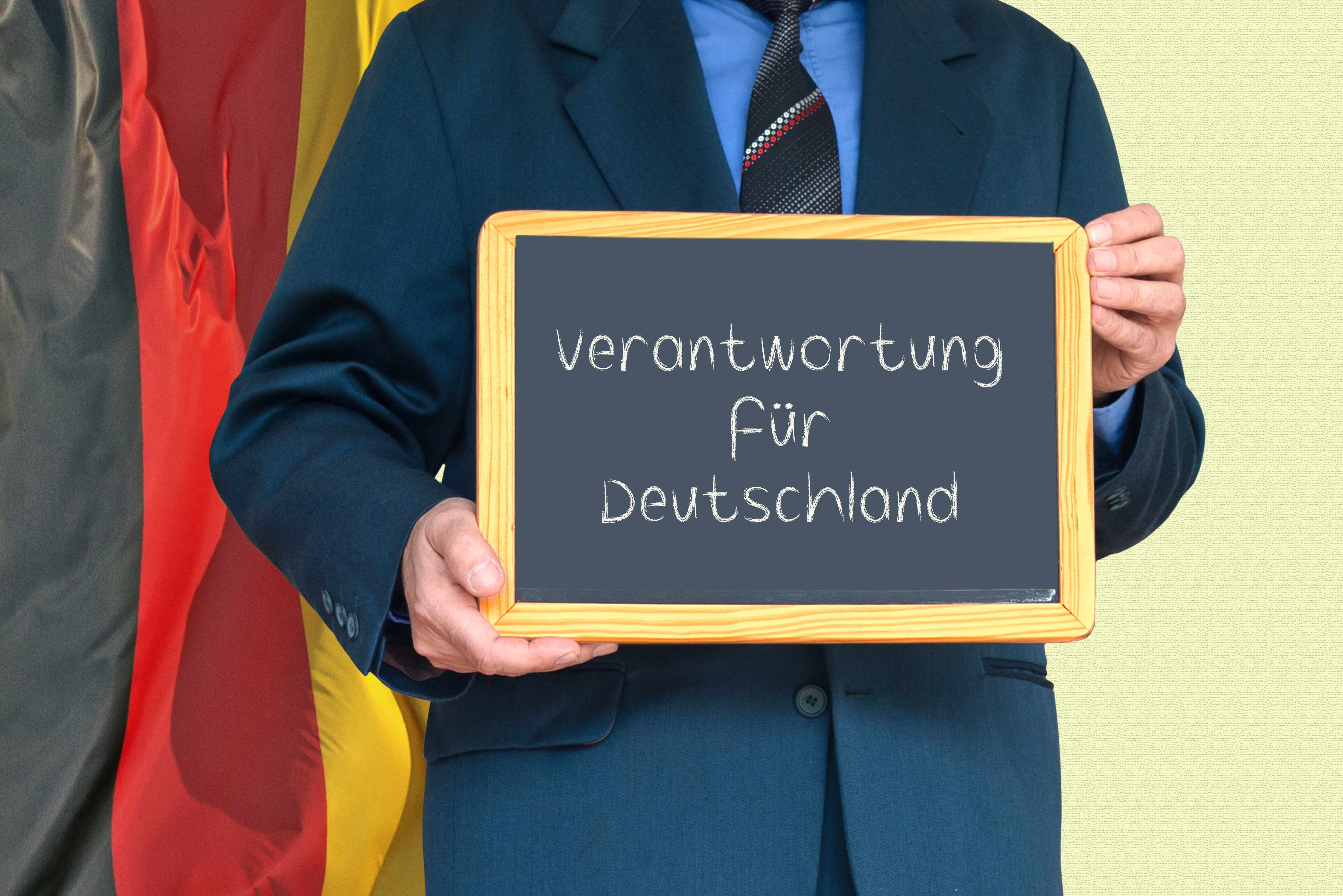 Ein Mann hält eine Tafel in den Händen, auf der mit Kreide geschrieben der Titel des Koalitionsvertrags steht