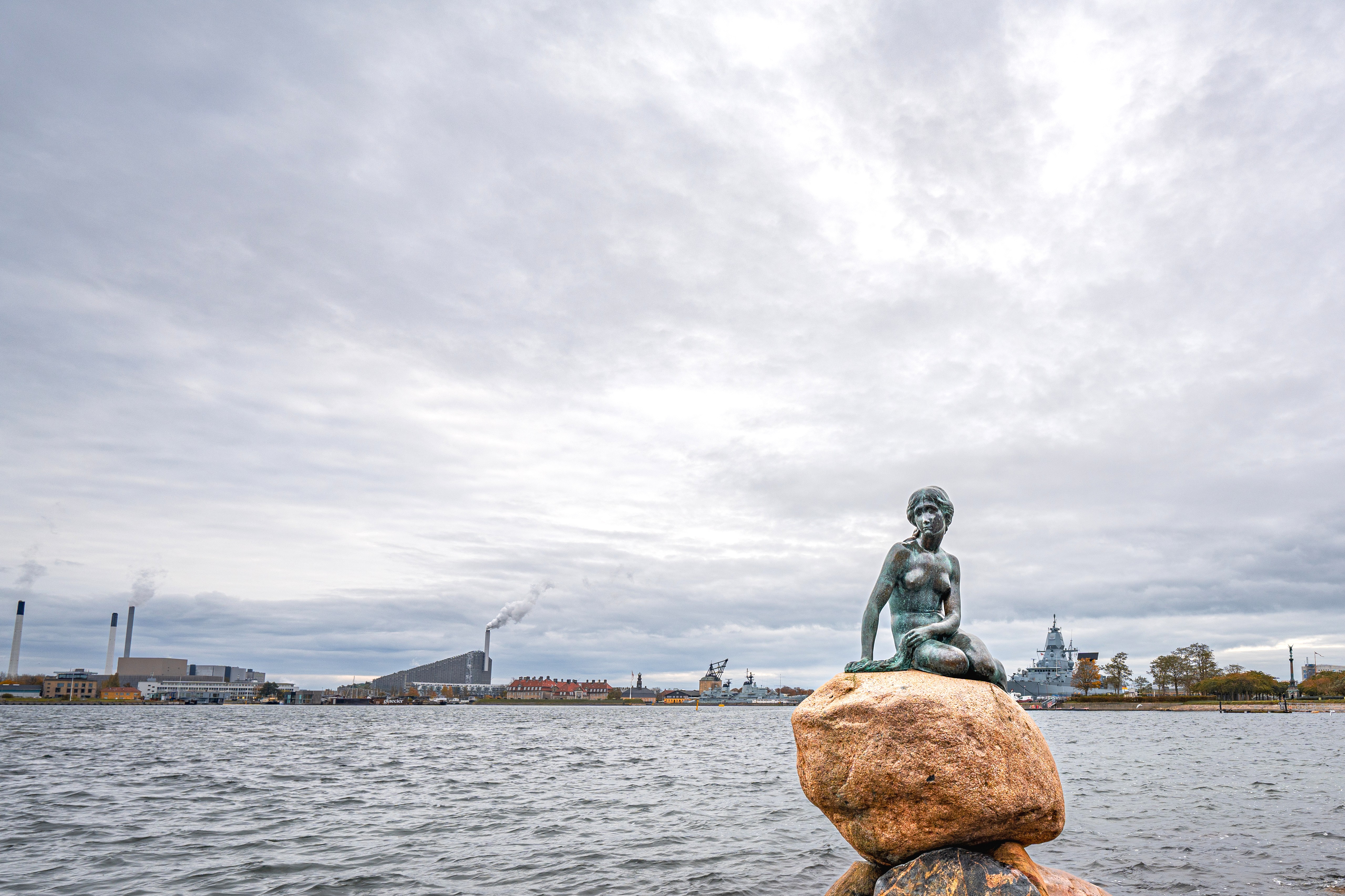 Skulptur der kleinen Meerjungfrau vor der Küste und Skyline Kopenhagens.